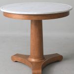 Fosbury Table A beautifully hand-crafted piece, the Fosbury Table blends marble and wood in a timeless French-inspired design. The Carrara marble top, detailed with a subtle grooved edge, adds understated elegance, while the central tapered column and tripod pedestal base recall the refined proportions of classic Empire style. Ideal as a statement table in a living or dining space, it balances form and function with effortless sophistication. Dimensions H 69 cm Ø 79 cm Weight 41 kg Materials Beech and Carrara marble